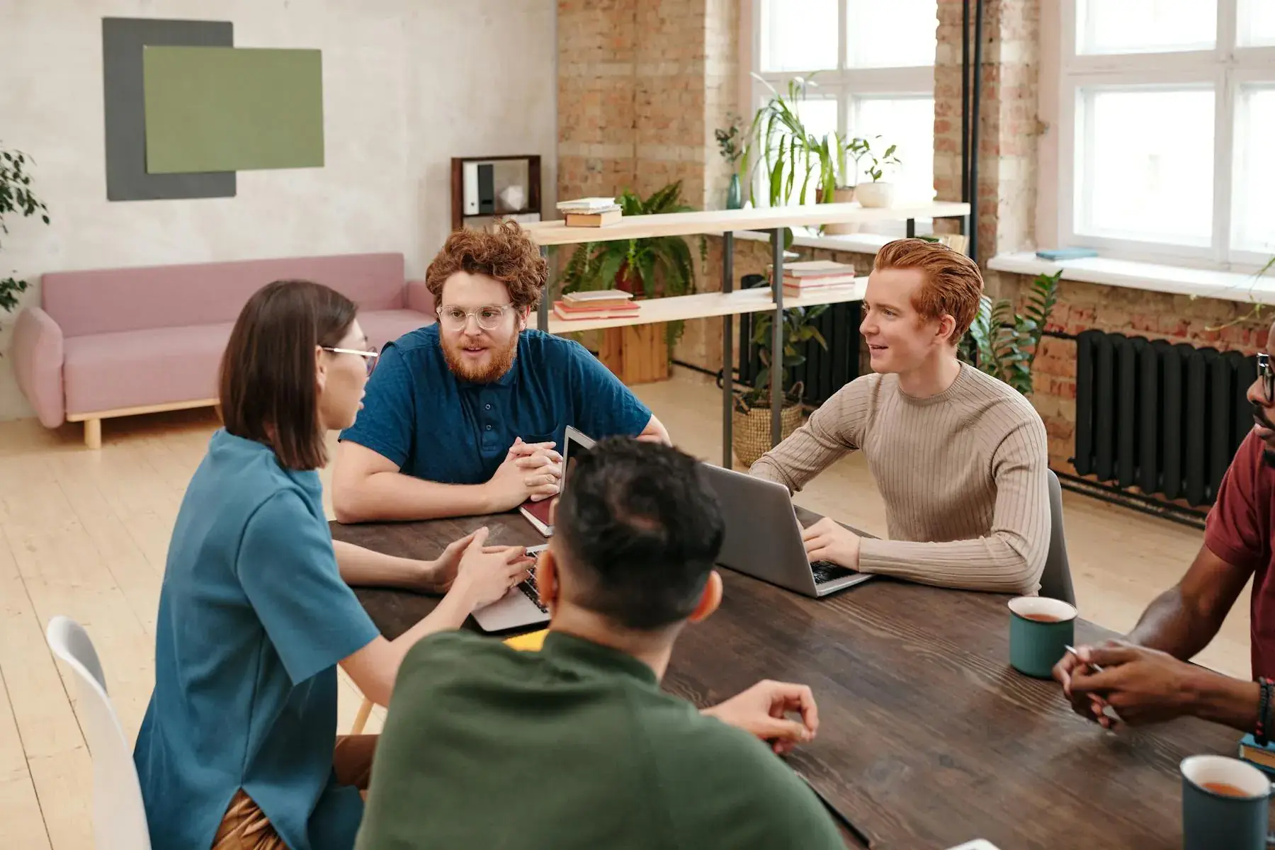 Team meeting around a work table representing MetClock partner and employee wellness access